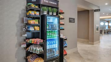 A vending machine with snacks and beverages, a sign for 'Pop' and 'Fizz Crunch', and a sign indicating a restroom.