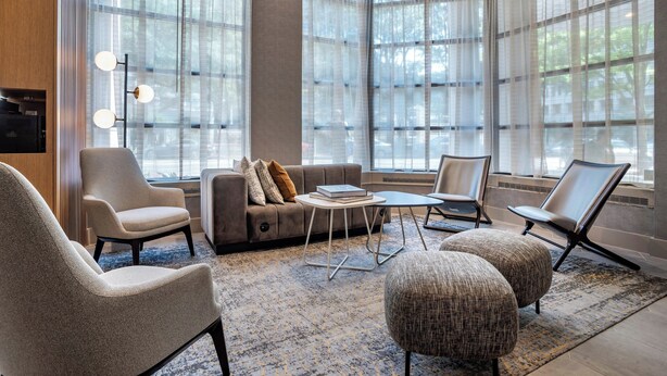 A modern living room with a sofa, armchairs, ottomans, and a coffee table.