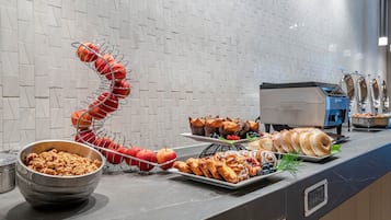 A buffet with various food items including fruits, pastries, and a bowl of cereal.