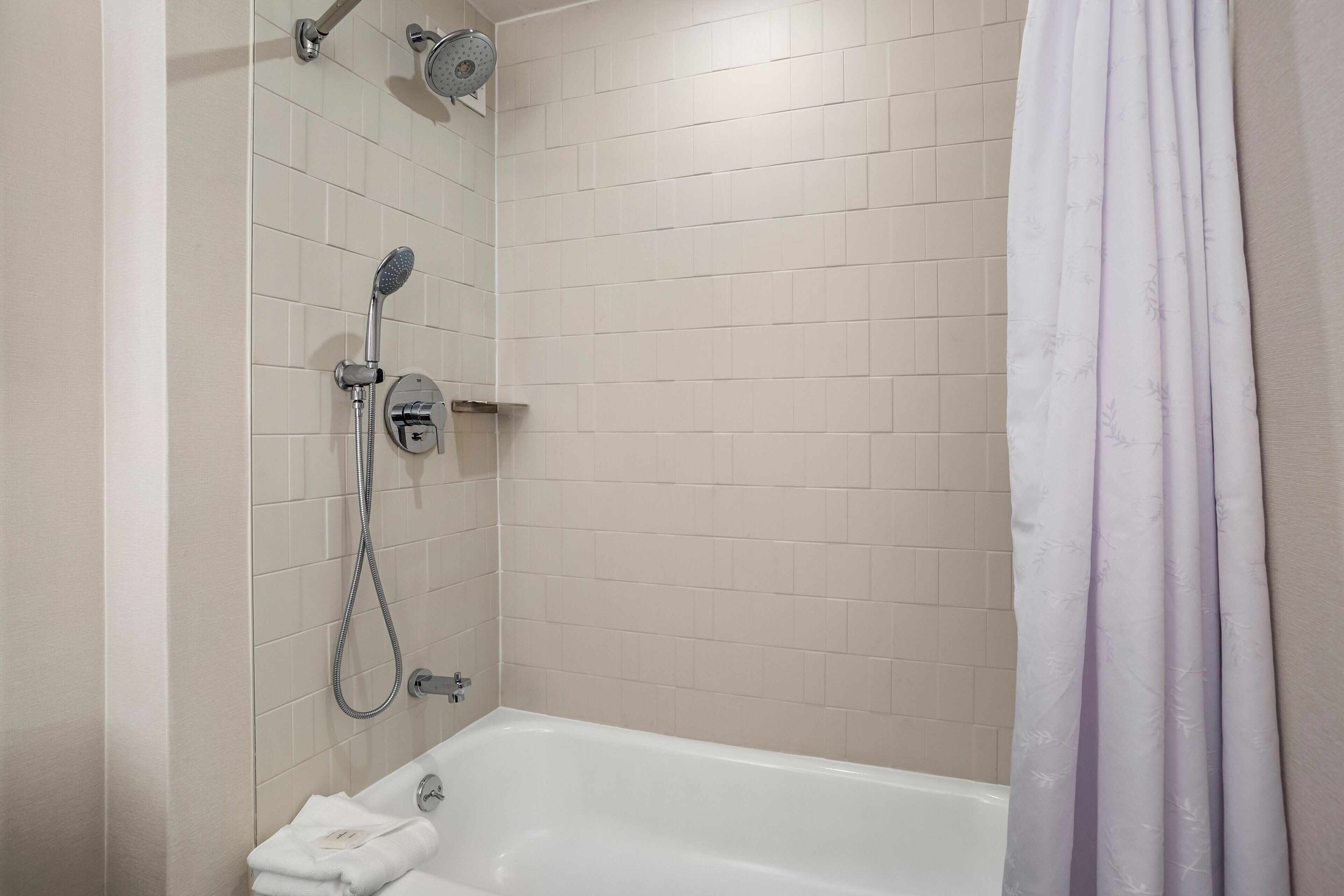 A bathroom with a bathtub, a showerhead, and a curtain.