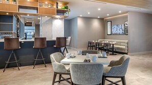 A modern dining area with a central table, bar stools, and a seating arrangement.