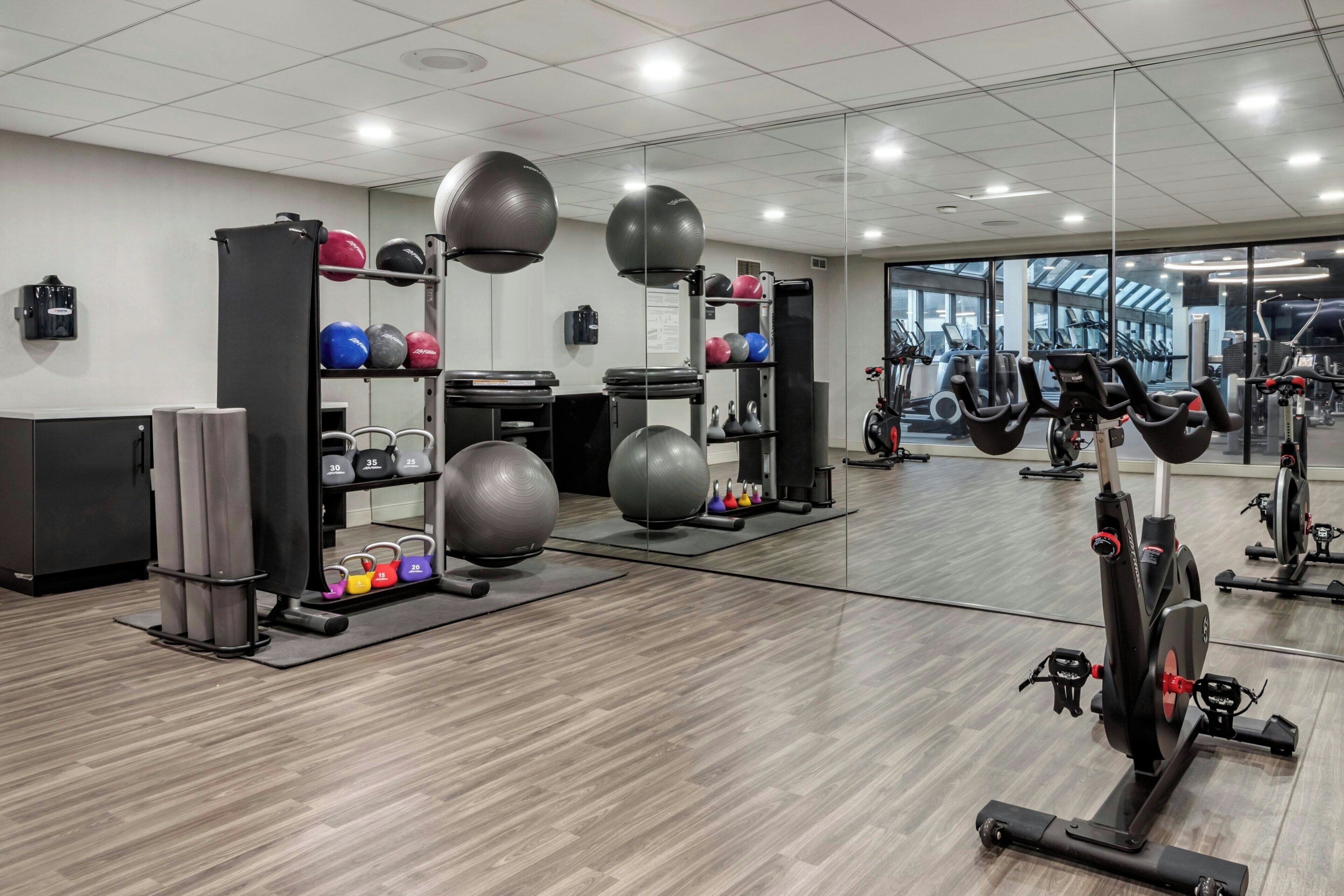 A gym with exercise equipment, a mirror, and a view of the outside.