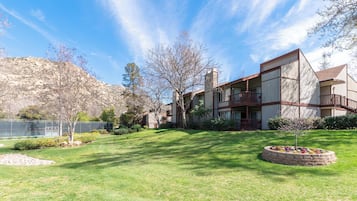 A modern building with a flat roof, a balcony, and a well-maintained lawn with a circular flower bed.