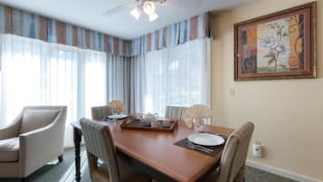 Un coin repas avec une table en bois, des chaises, un ventilateur de plafond et un tableau accroché au mur.