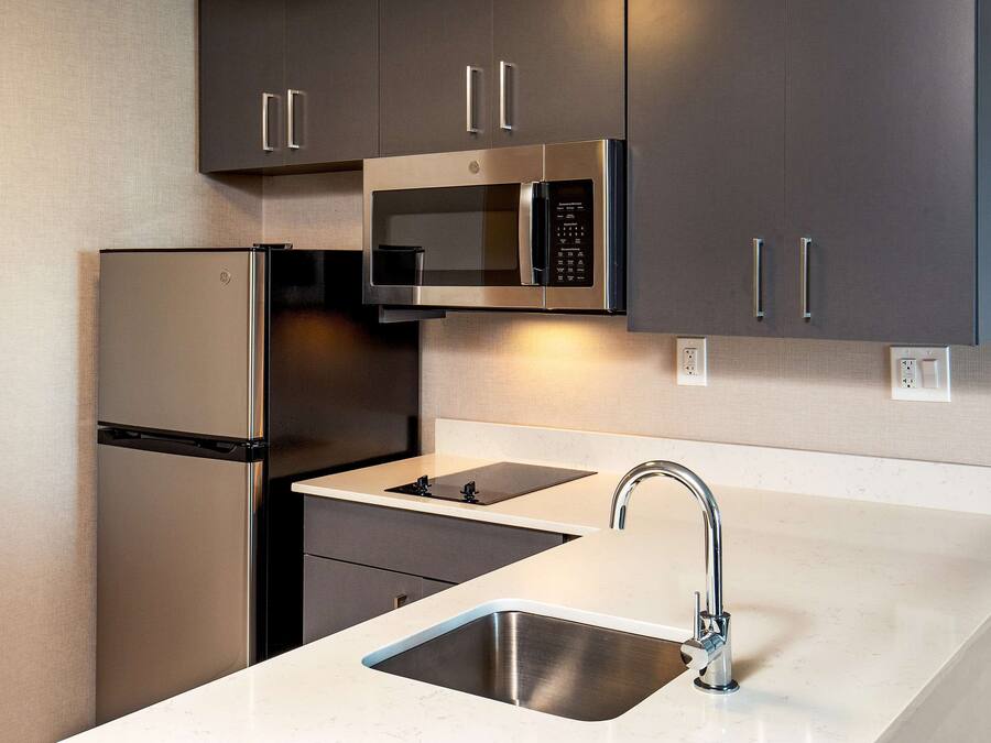 Una cucina moderna con elettrodomestici in acciaio inox, un lavello doppio e mobili scuri.