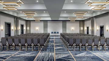 A conference room with rows of chairs, a patterned carpet, and modern lighting fixtures.