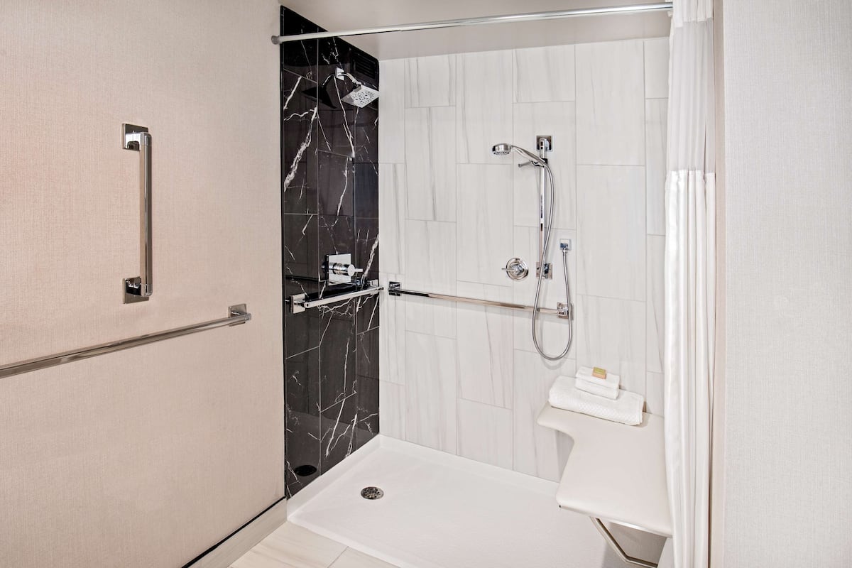Une salle de bain moderne avec une douche à l’italienne, une porte en verre et un lavabo blanc doté d’un porte-serviettes.
