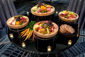 A round table with three wooden platters of assorted cheeses, meats, and fruits, surrounded by candles. - DoubleTree by Hilton Washington DC North/Gaithersburg (Gaithersburg)