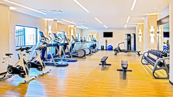 Un gimnasio moderno con máquinas de cardio, estaciones de pesas y un muro de espejos.