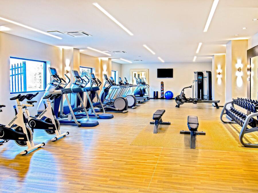 Un gimnasio moderno con máquinas de cardio, estaciones de pesas y un muro de espejos.
