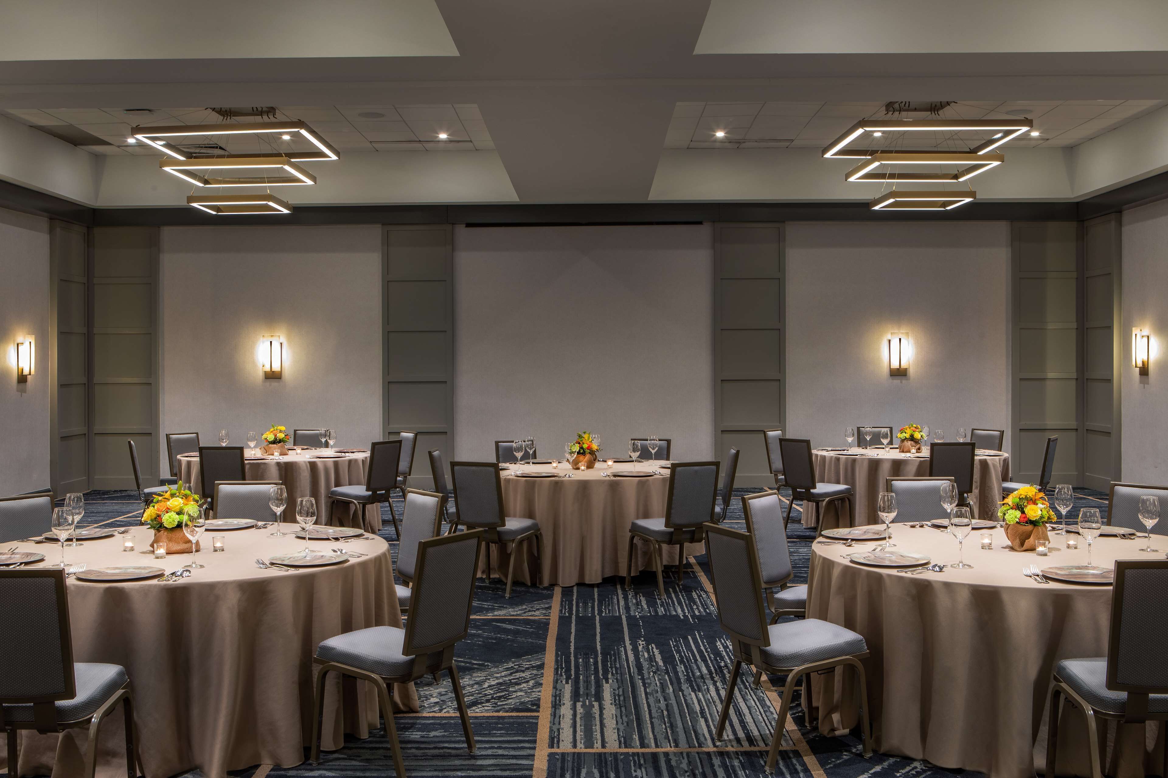 A conference room with round tables, chairs, and floral centerpieces.