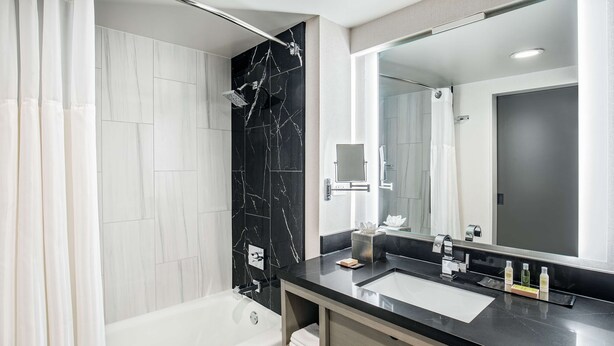 A modern bathroom with a bathtub, a large mirror, and a black marble backsplash.