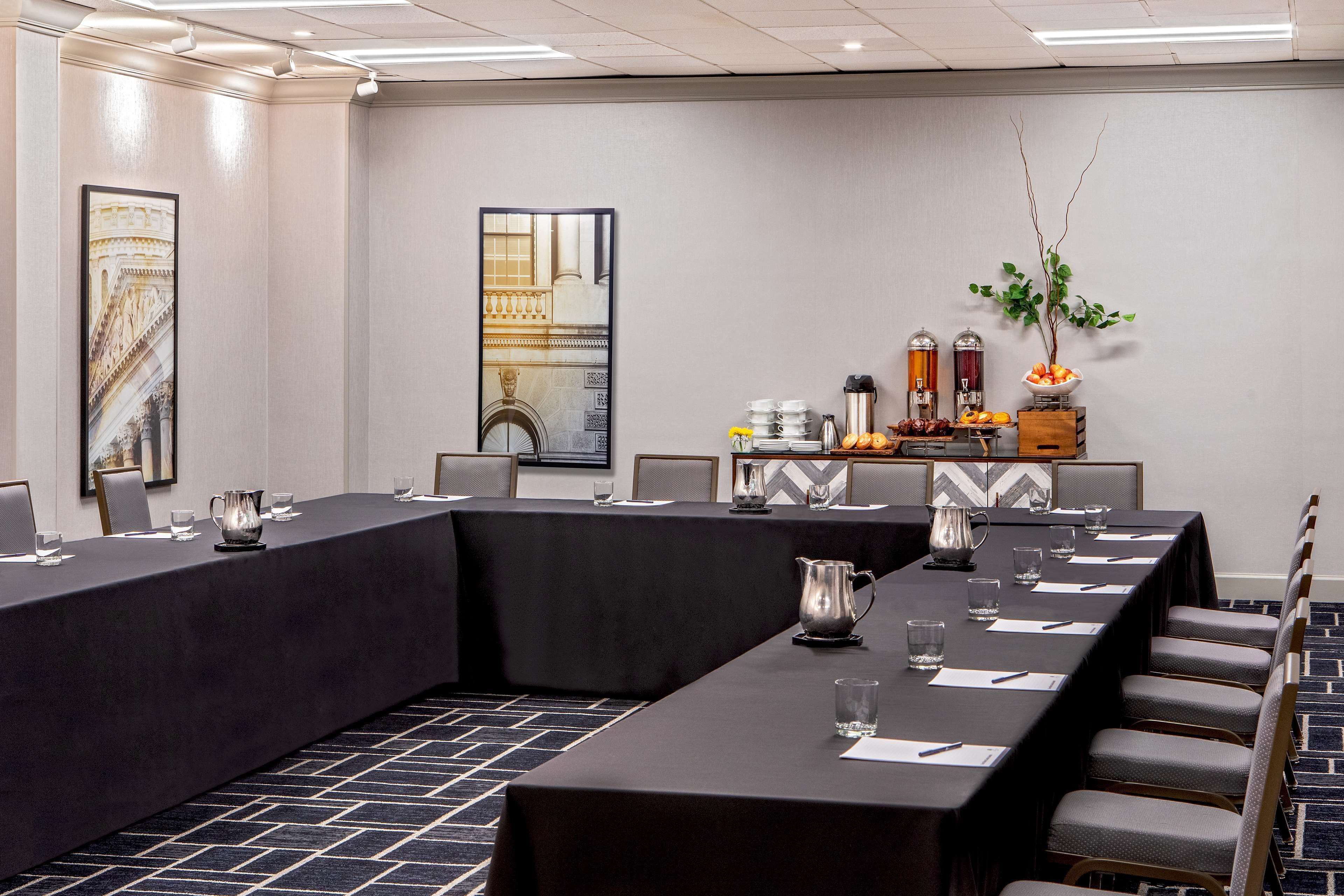 A conference room with a long table, chairs, and a coffee station.