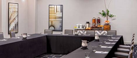 A conference room with a long table, chairs, and a coffee station.