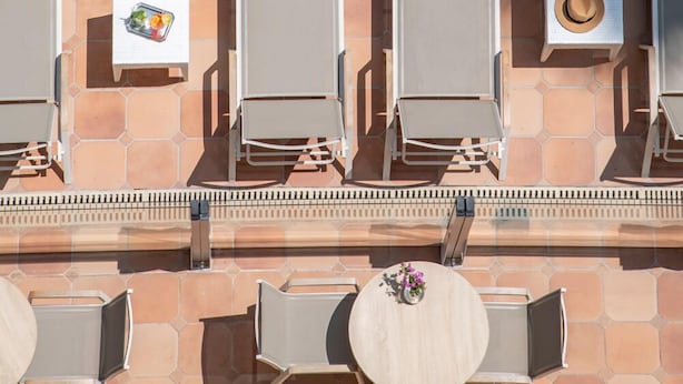 An aerial view of a poolside area with lounge chairs and a table, each with a towel and a small item on the table. - Le Cetai Cannes Beach Hotel (Cannes)