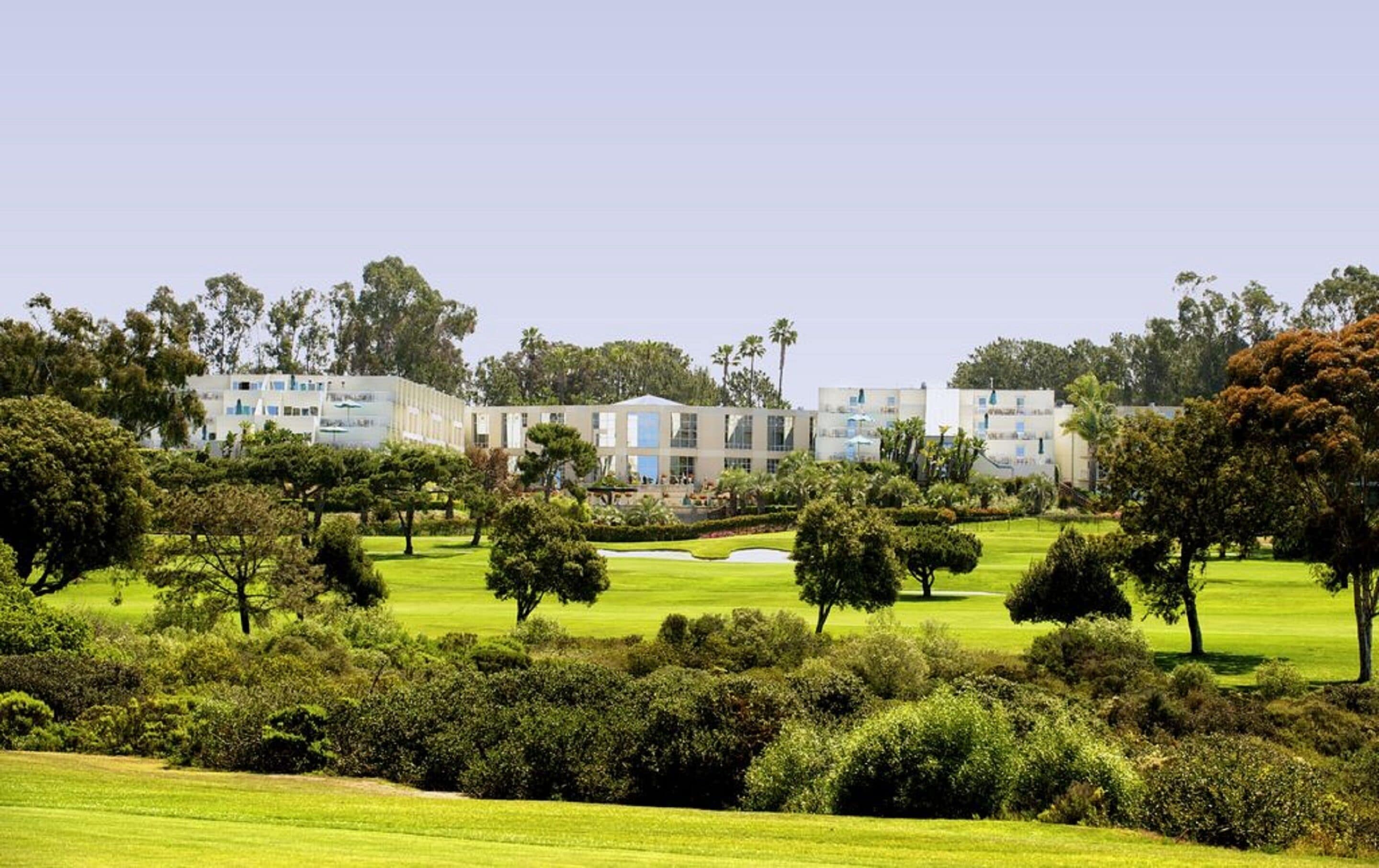 Un terrain de golf avec un club-house et des immeubles résidentiels en arrière-plan.
