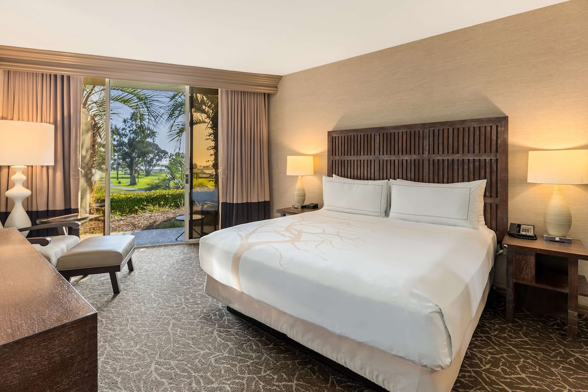 A hotel room with a large bed, two bedside tables with lamps, a desk, and a chair.