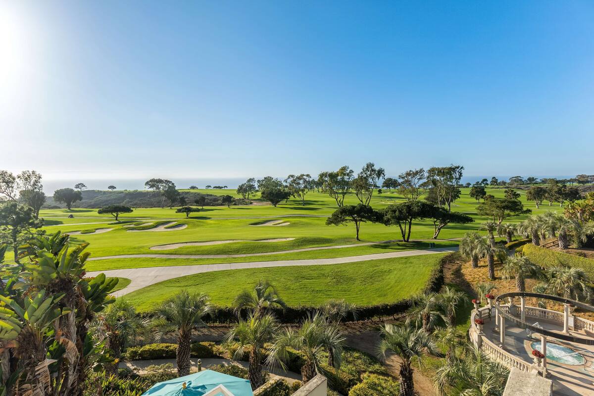 A golf course with a pool area and palm trees.