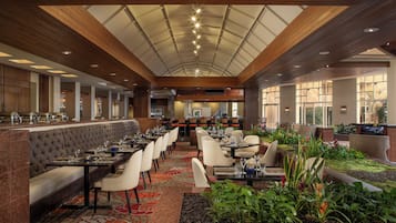 A spacious restaurant with high ceilings, a central seating area, and a view of the outdoors.
