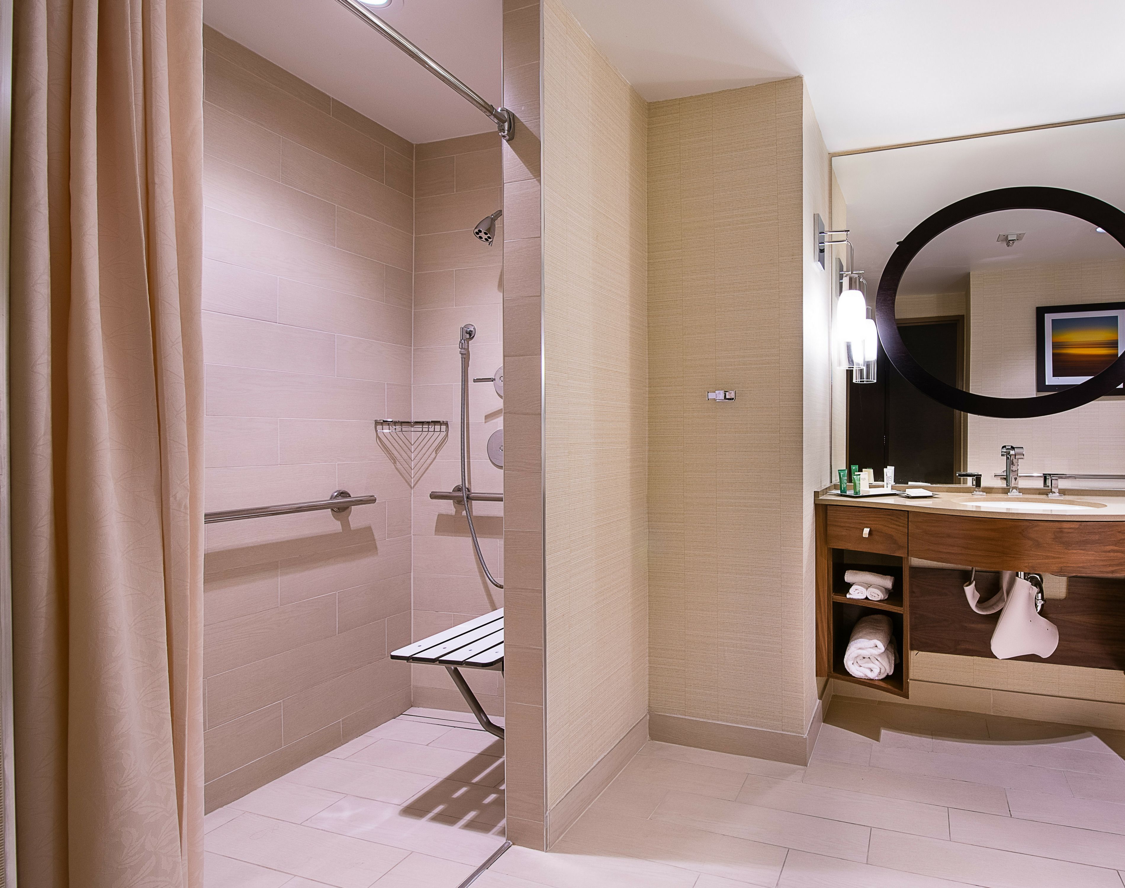 A modern bathroom with a shower, a vanity with a mirror, and a towel rack.