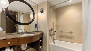 A modern bathroom with a double sink vanity, a large mirror, a shower with a glass door, and a bathtub.