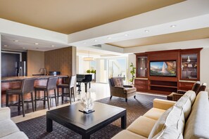 A modern living room with a sofa, a coffee table, a TV, and a piano. - Hilton La Jolla Torrey Pines (La Jolla)