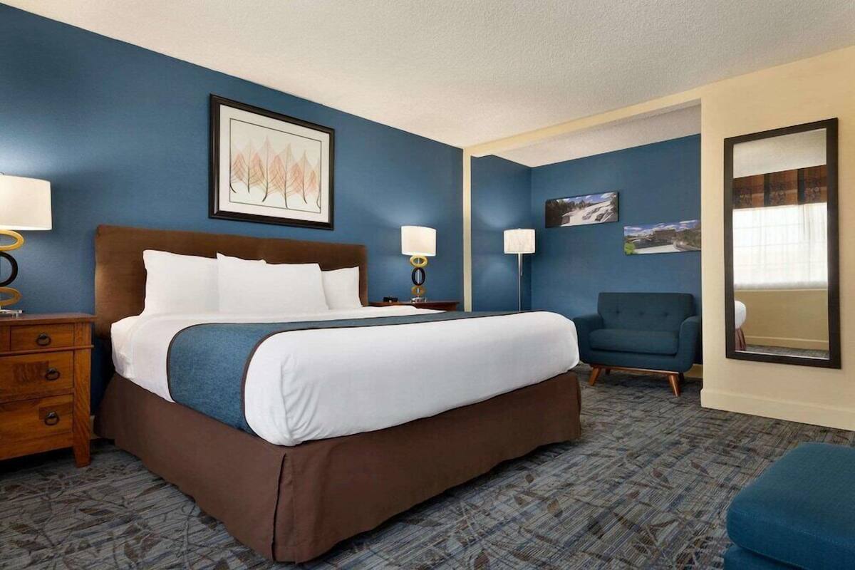 A hotel room with a large bed, two bedside tables, a chair, and a mirror.