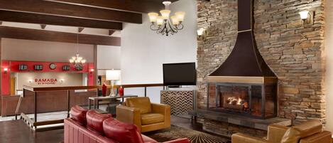 A modern living room with a stone fireplace, leather sofas, and a wooden ceiling.