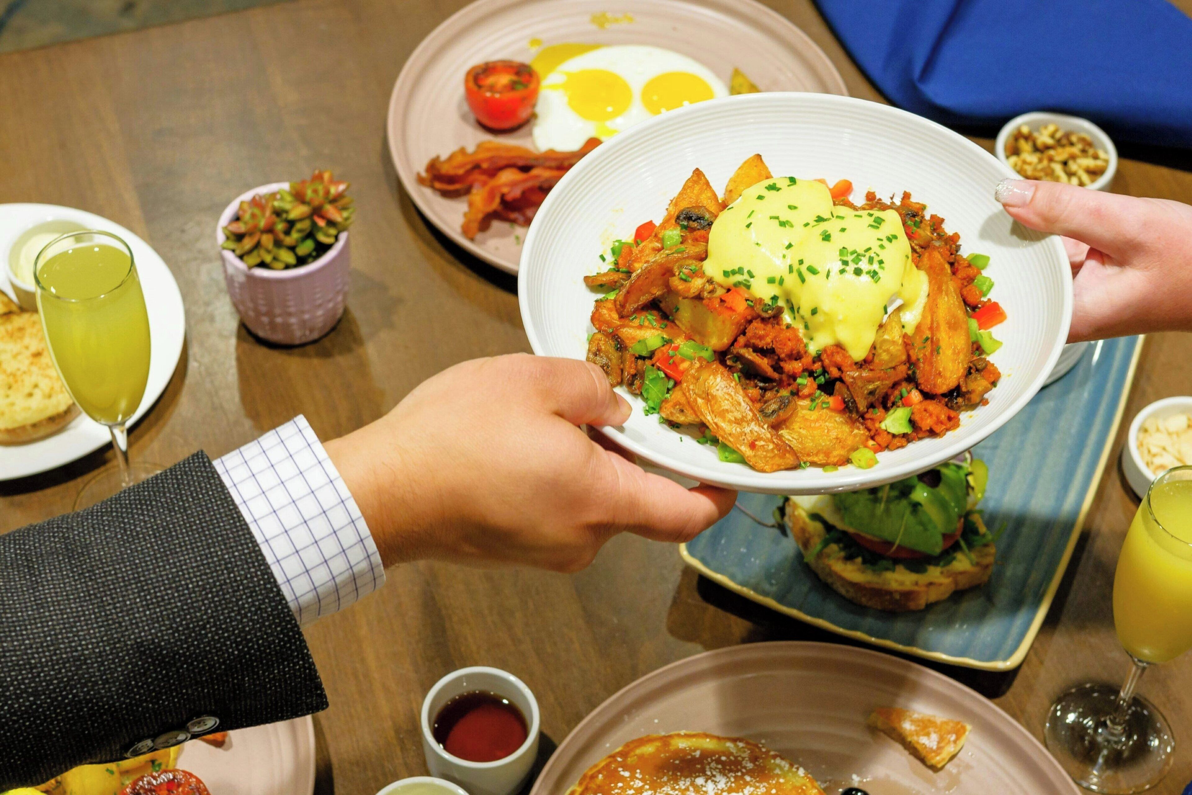 A dining table with various dishes including a plate of food, a glass of juice, and a small bowl of condiments.
