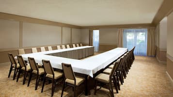 A conference room with a long table and chairs, beige walls, and a carpeted floor.