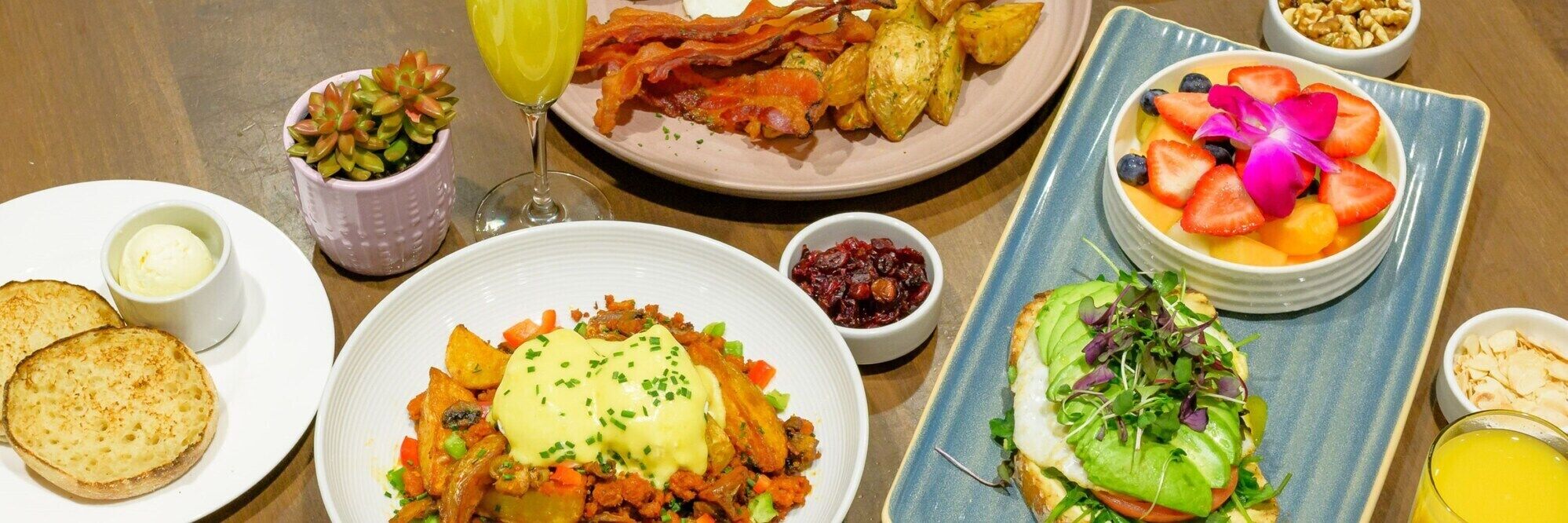 A breakfast buffet with various dishes including eggs, potatoes, and fruits.