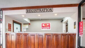 A registration desk with a wooden counter, a sign above it, and a red carpet. - Econo Lodge Dyersburg I-155 (Dyersburg)