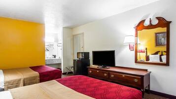 Una habitación de hotel con dos camas, televisión, cómoda y espejo.