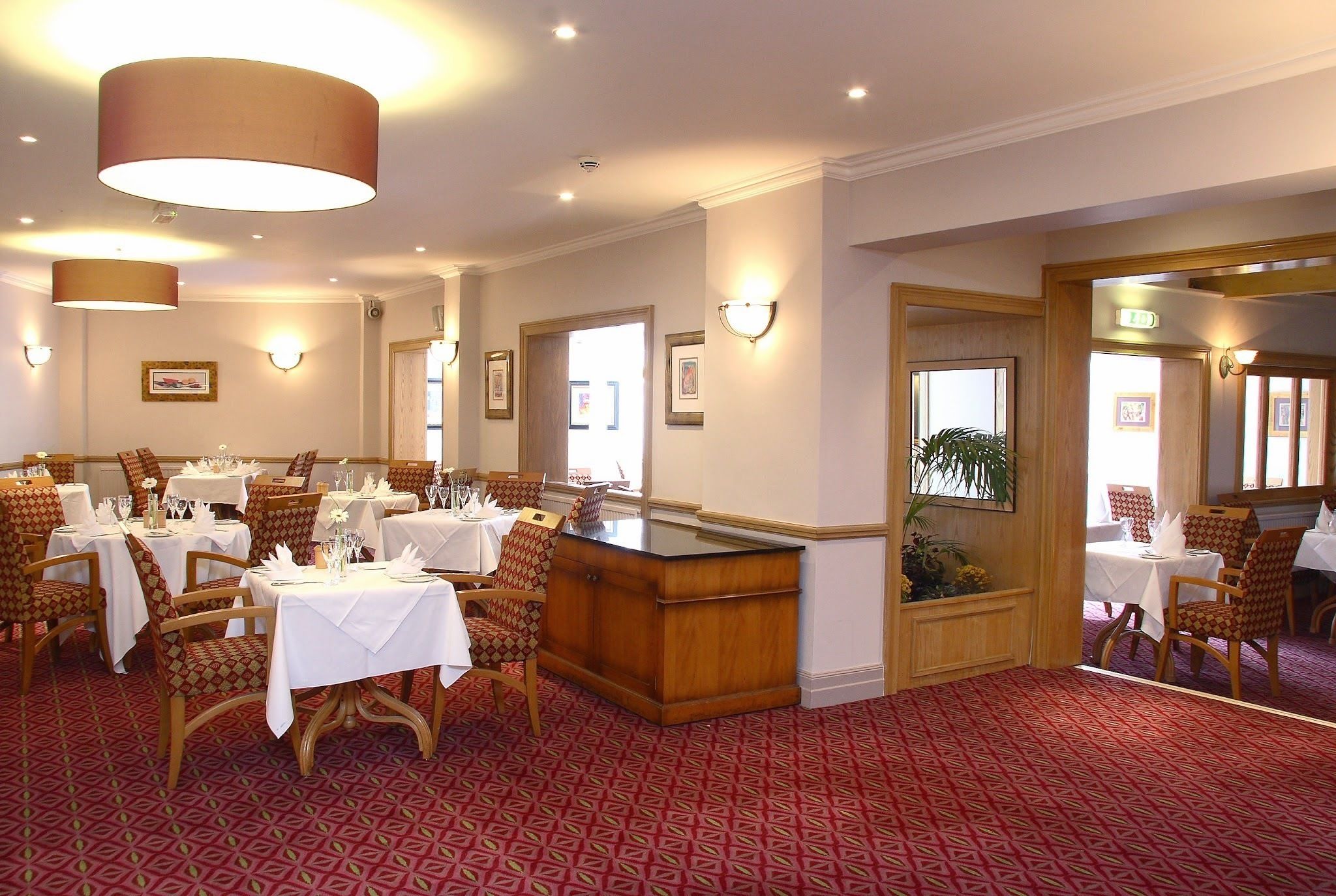 A dining area with tables set for a meal, wooden chairs, and a bar counter.