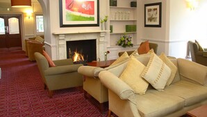 Una sala acogedora con chimenea, asientos cómodos y una estantería.
