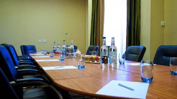 Una sala de conferencias con una larga mesa, sillas y diversos objetos como botellas, vasos y frutas.