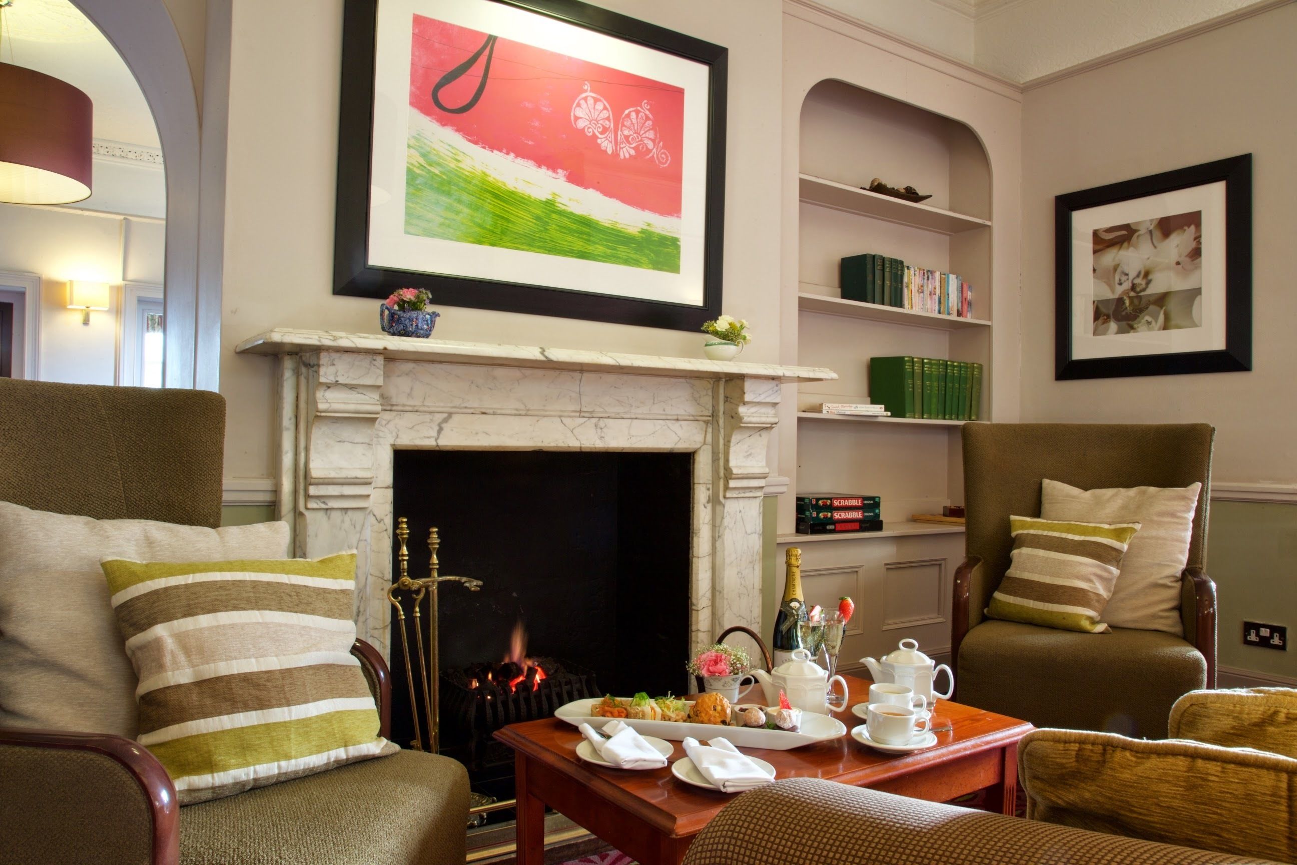 Un salón acogedor con chimenea, asientos cómodos, una mesa de centro con juego de té y estanterías.