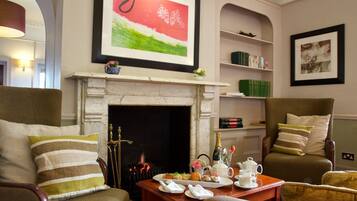 Un salón acogedor con chimenea, asientos cómodos, una mesa de centro con juego de té y estanterías.