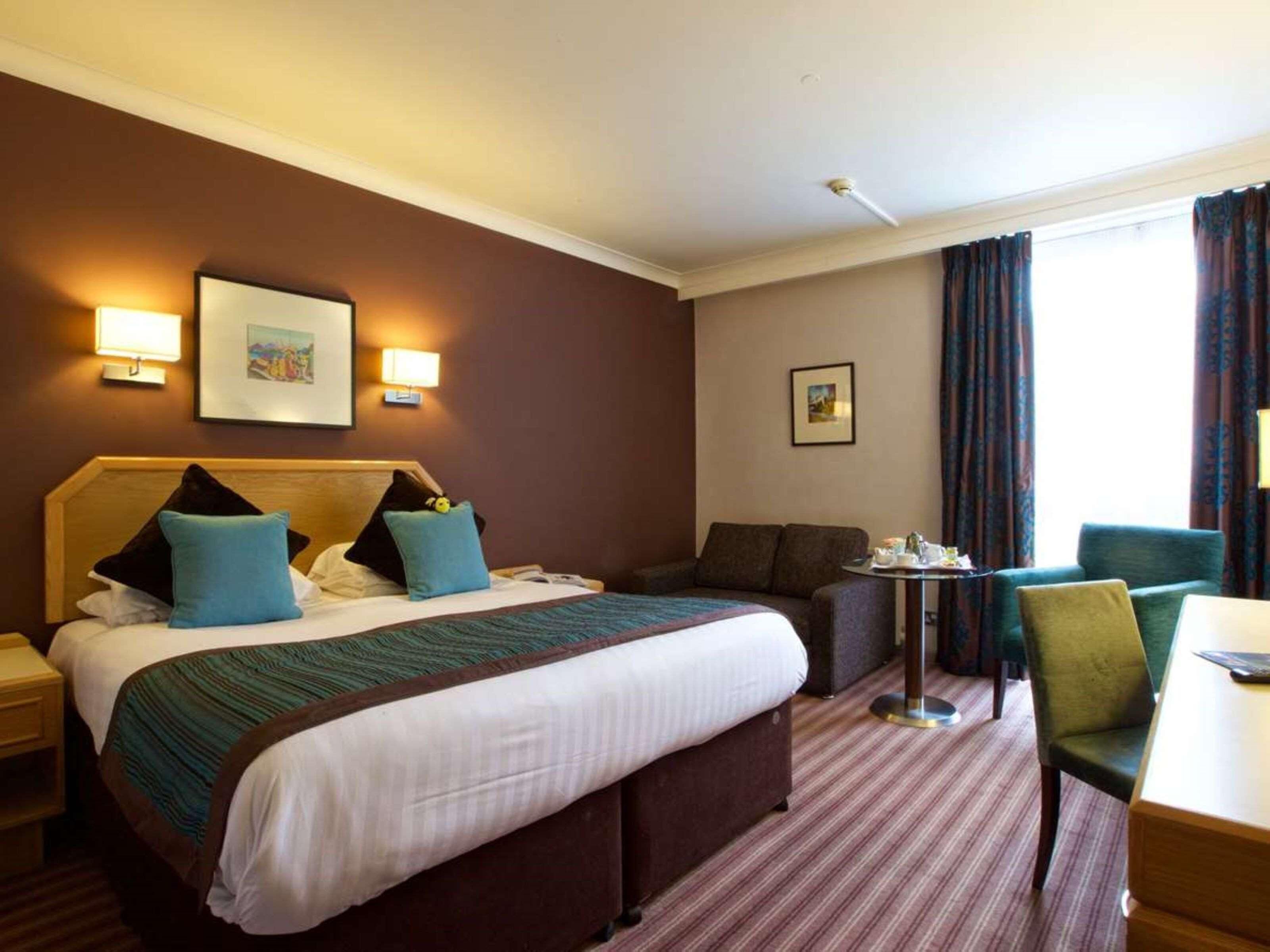 Ein Hotelzimmer mit Bett, einer Couch, einem kleinen Tisch und einem Stuhl.