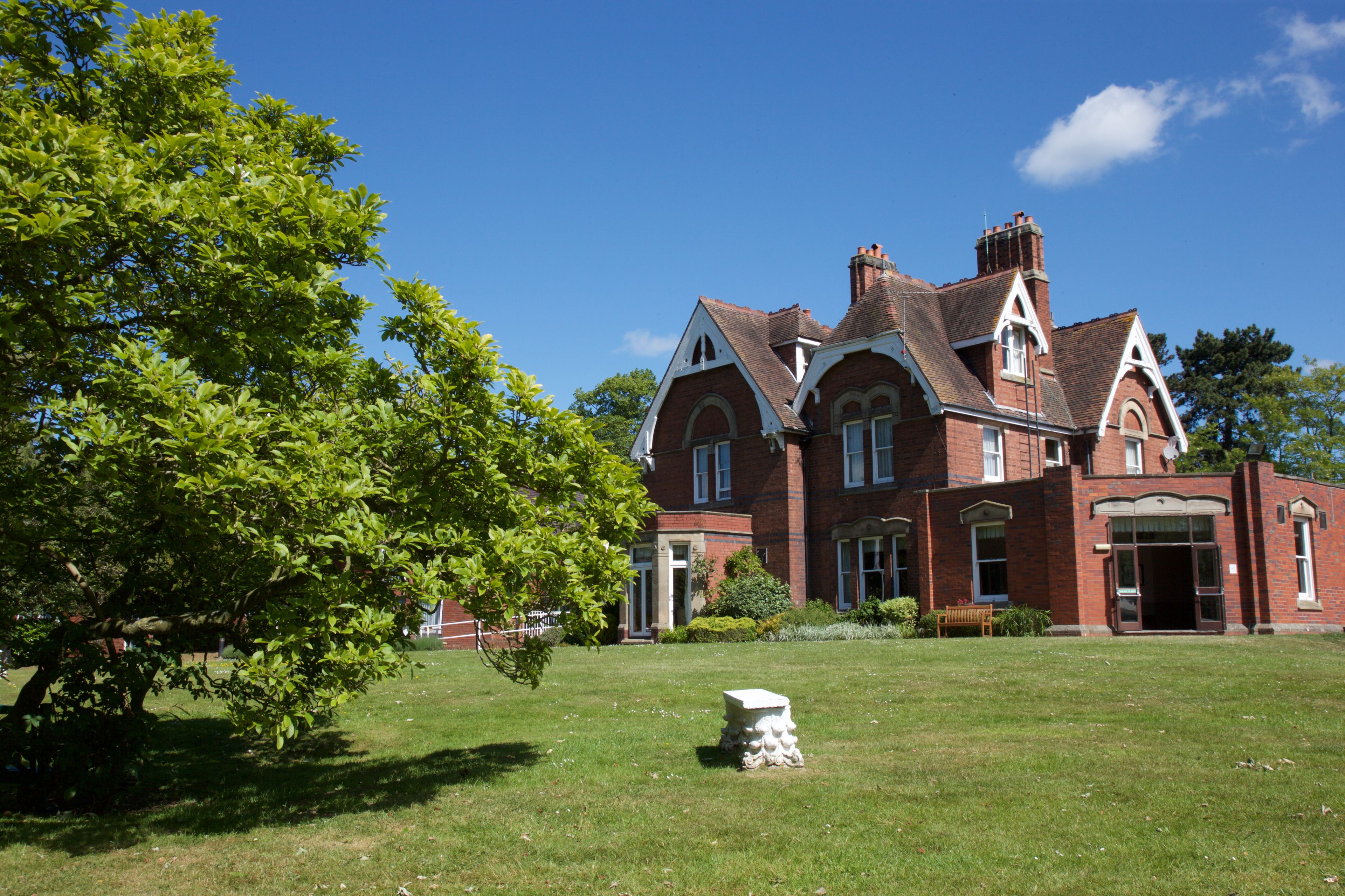 A large, historic red brick building with a symmetrical facade, multiple windows, and a central entrance.