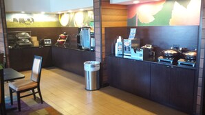 A restaurant with a counter, chairs, a trash can, and a coffee machine.