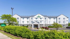 A multi-story Wingate by Wyndham hotel with a central entrance, parking lot, and well-maintained landscaping.