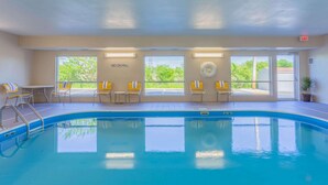 An indoor swimming pool with clear glass walls, yellow chairs, and a 'NO DIVING' sign.