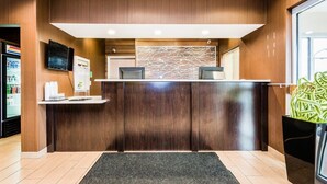 A reception desk with a modern design, a flat-screen TV, and a decorative wall piece.