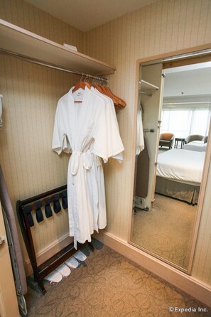 A hotel room with a walk-in closet, a bed, and a large mirror.