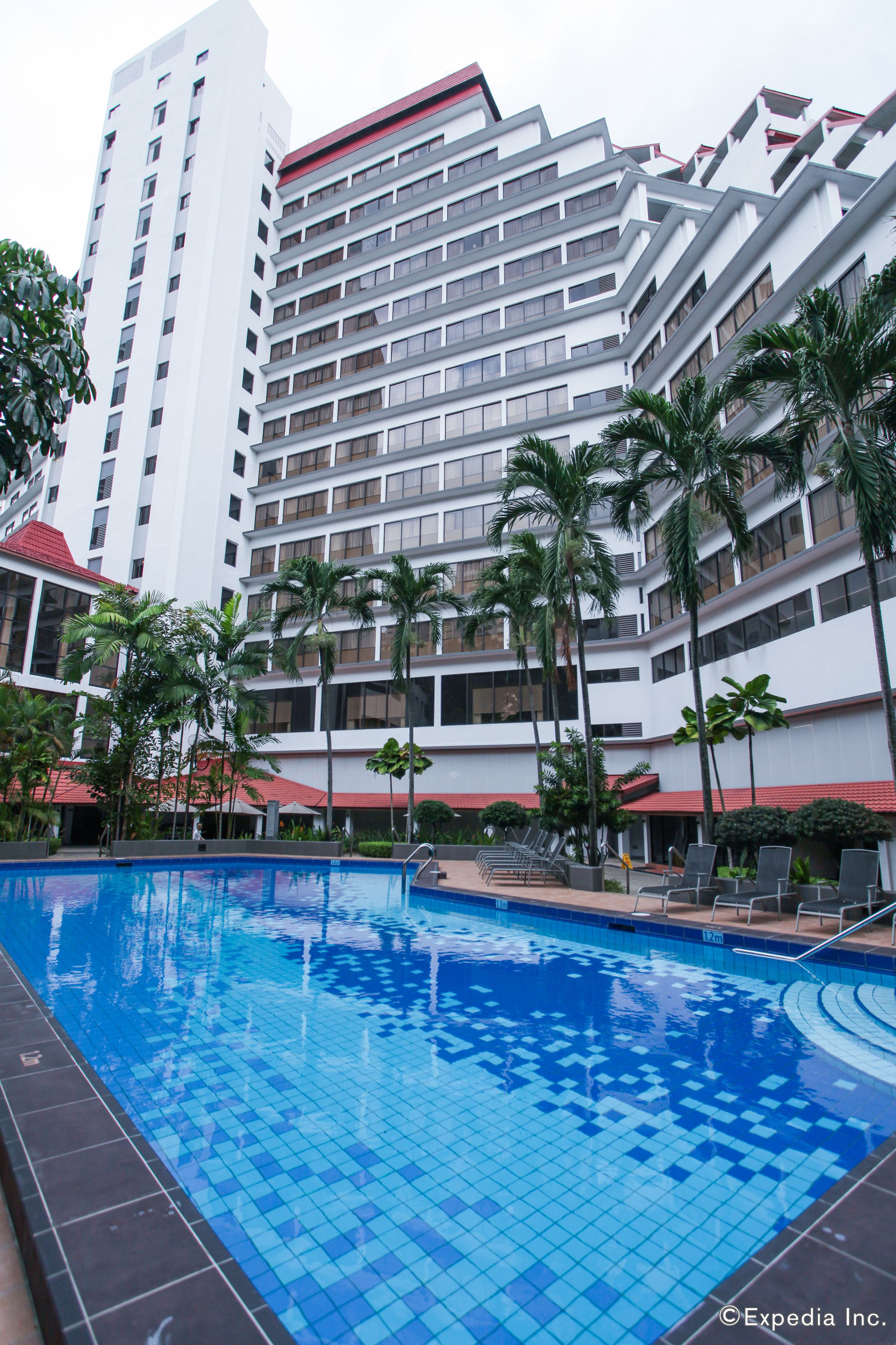 A hotel with a swimming pool, palm trees, and a modern architectural design.