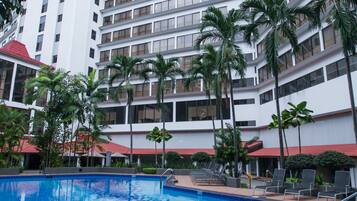 A hotel with a swimming pool, palm trees, and a modern architectural design.
