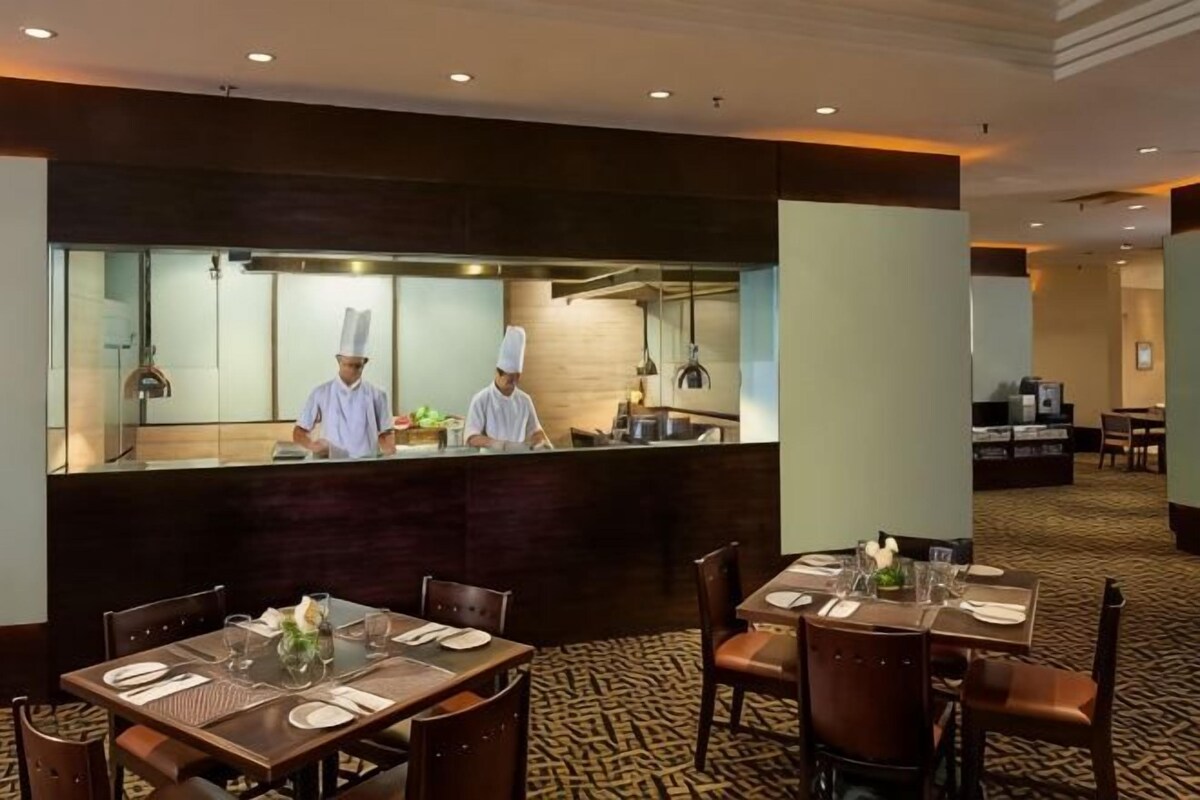 A restaurant with a counter, tables, and chairs.