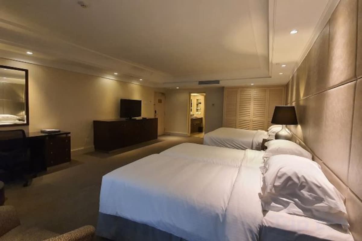 A hotel room with two beds, a TV, a dresser, and a mirror.