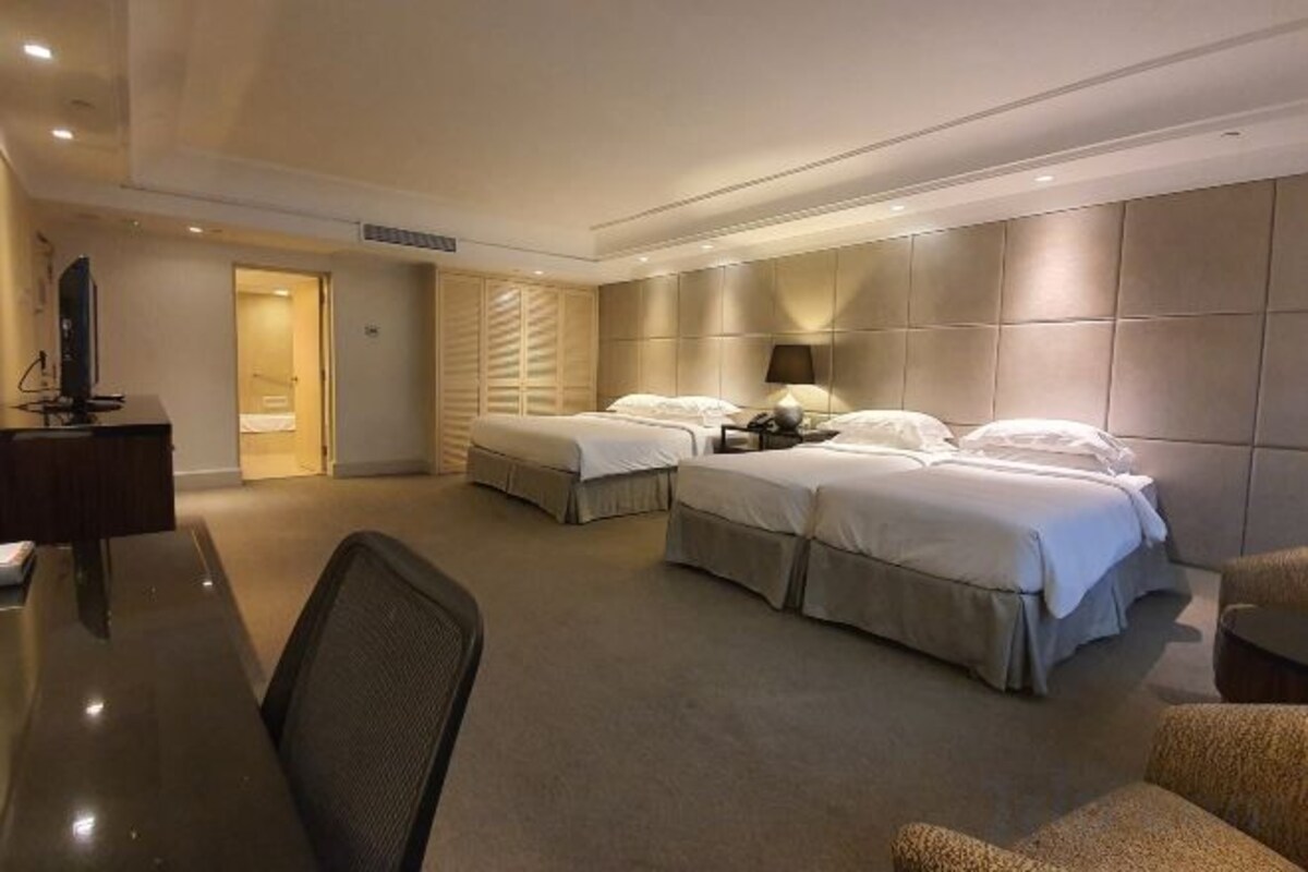 A hotel room with two beds, a desk, and a chair.